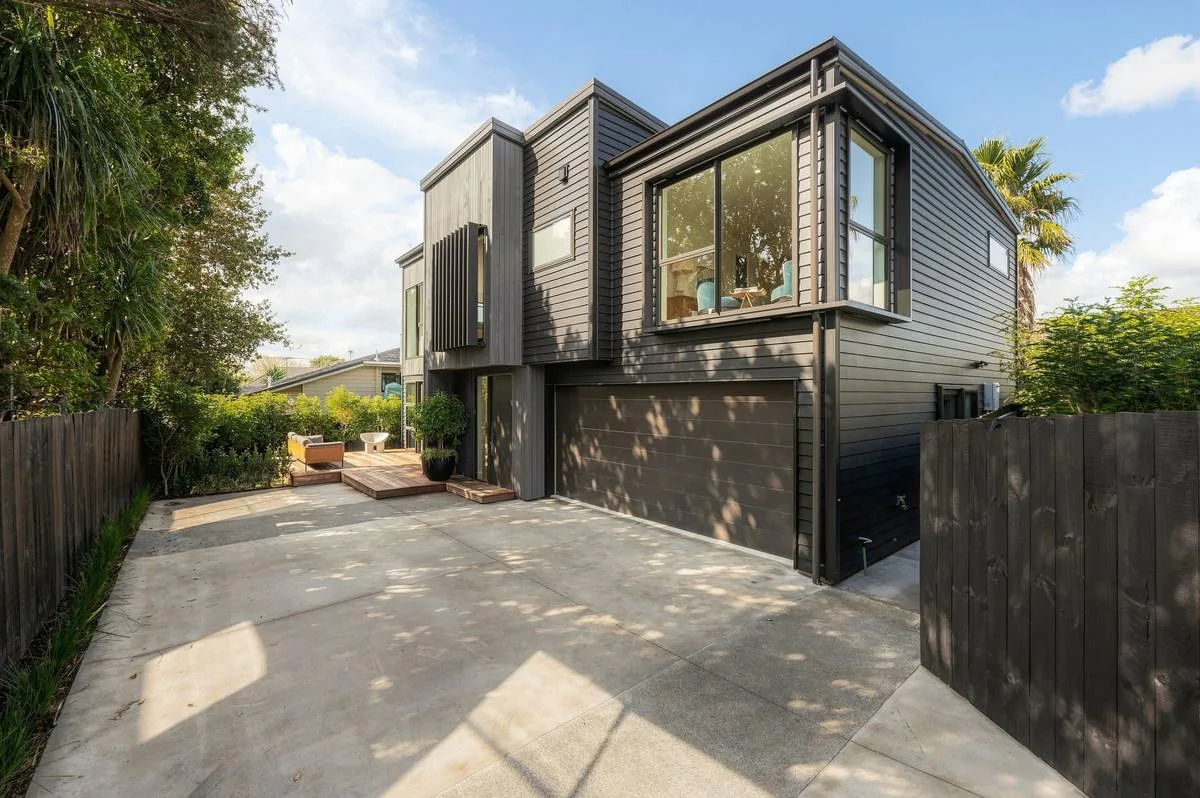 Dark cedar-clad Auckland home photographed on the approach, in the editorial style
