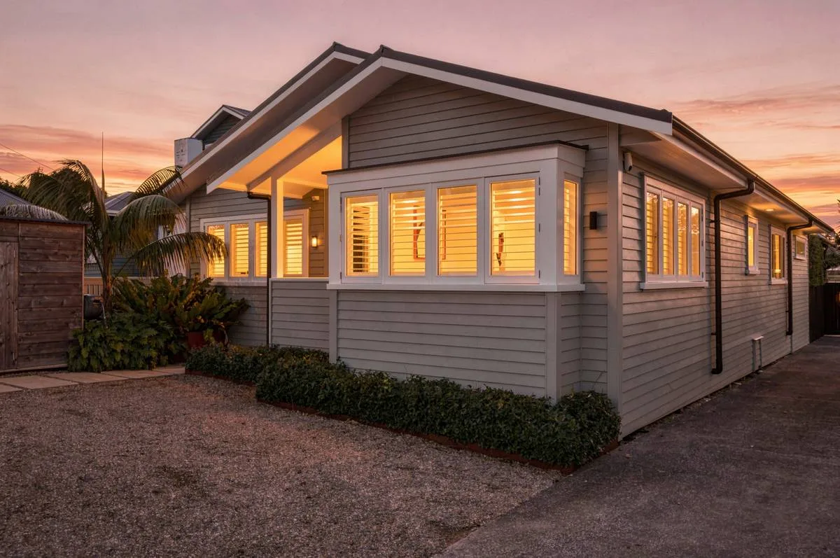 Auckland home photographed at twilight, exterior lit against a blue hour sky
